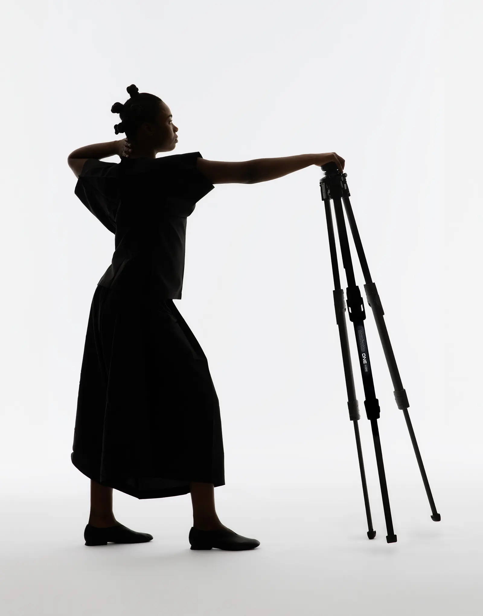 A person posing with the ONE tripod by leading industrial design consultancy LAYER on a white background.
