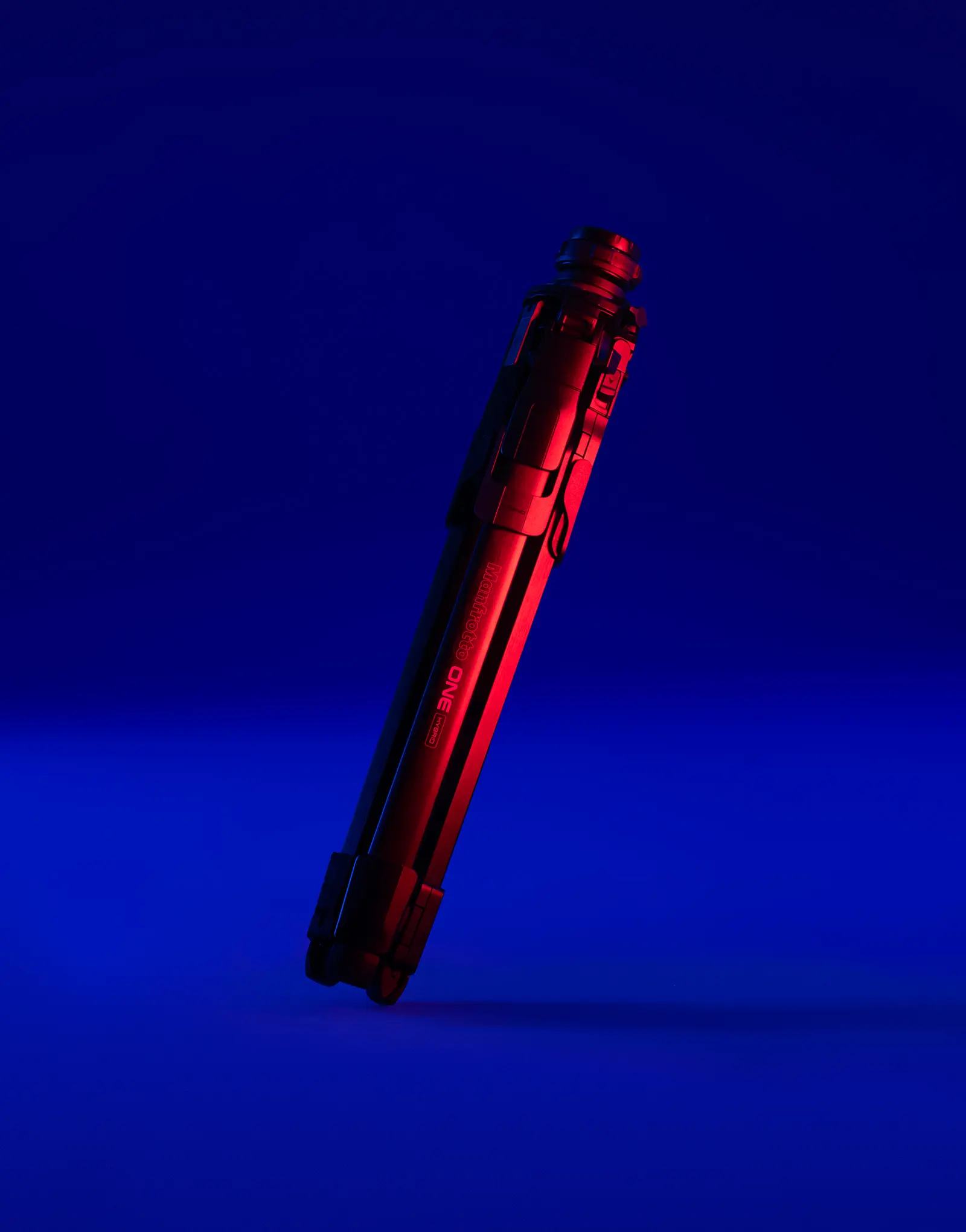 The ONE tripod by leading industrial design consultancy LAYER shown folded, lit dramatically against a blue background.